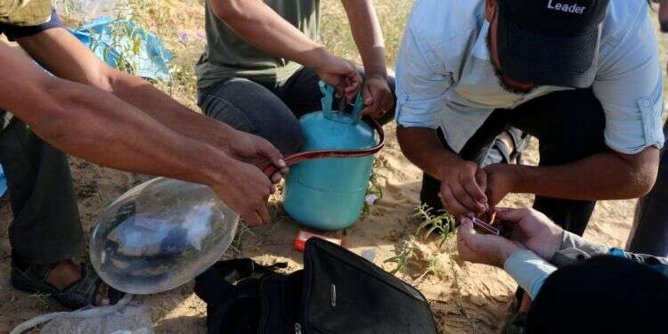 מחבלים מכינים בלוני נפץ. צילום: AFP "יש לתת לצה"ל הנחיה לירות כדי לפצוע ולא להרוג"