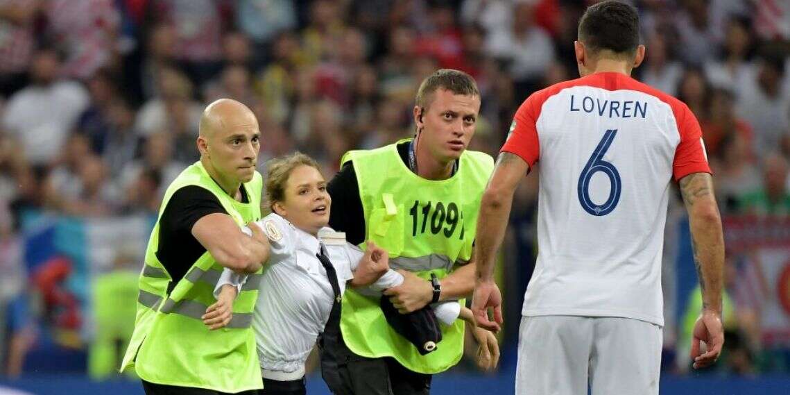 המאבטחים גוררים את חברת הלהקה מחוץ למגרש. לוברן מתצפת. צילום: EPA צילום: EPA