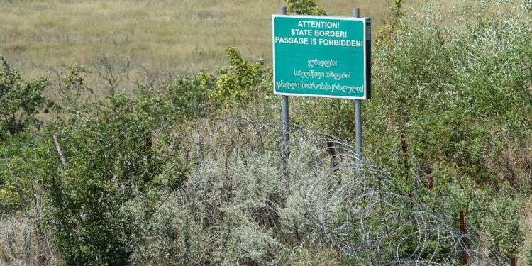 שלט אזהרה לצד גדר תיל שהקימו הכוחות הרוסיים לסימון הגבול הדה-פקטו עם גאורגיה. צילום: AFP צילום: AFP