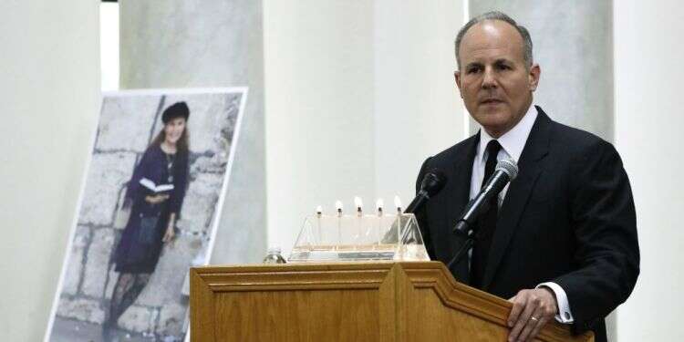 אילן קאר נושא דברים בהלווייתה של לורי גילברט קיי, לצד תמונתה. צילום: AP צילום: AP