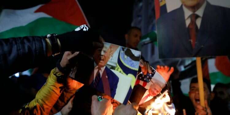 מפגינים ברמאללה מציתים את תמונת טראמפ בעקבות פרסום התוכנית. צילום: AFP צילום: AFP