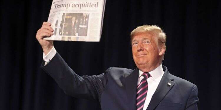 טראמפ מציג עיתון שכותרתו מכריזה על הזיכוי בסנאט. צילום: AFP טראמפ אחרי הזיכוי בסנאט: מושחתים פעלו לחבל בנו