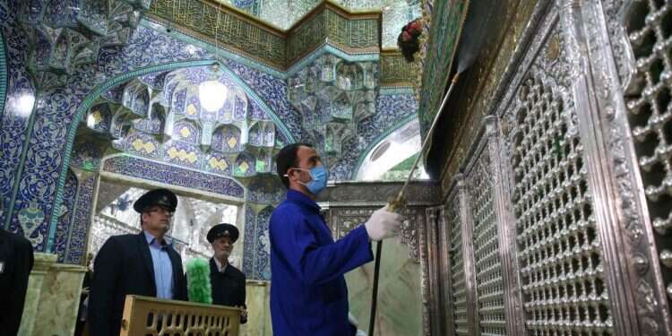 חיטוי אתר דתי בקום, איראן. צילום: AFP הפרלמנט הושבת, תפילות בוטלו: איראן מנסה להיאבק בקורונה