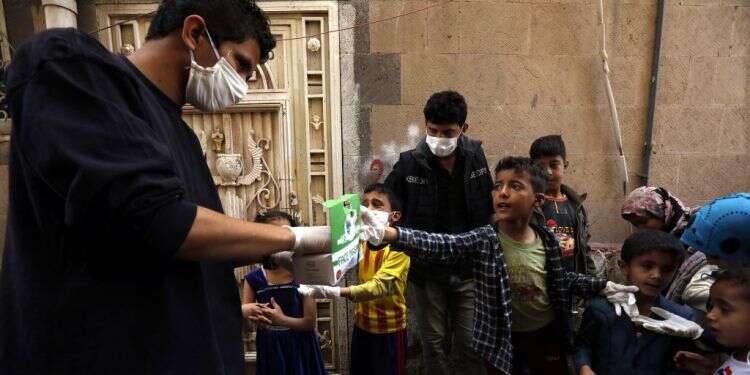 מתנדב מחלק מסכות פנים לילדים בצנעא, תימן. צילום: אי.פי.איי בתימן "אין חולי קורונה", אבל הכולרה הורגת המונים