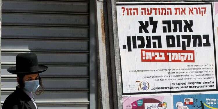 כרזה נגד יציאה לרחוב בבני ברק, אתמול. צילום: AFP מודיעין, הסברה, סיוע: תוכנית השלבים של צה"ל בבני ברק