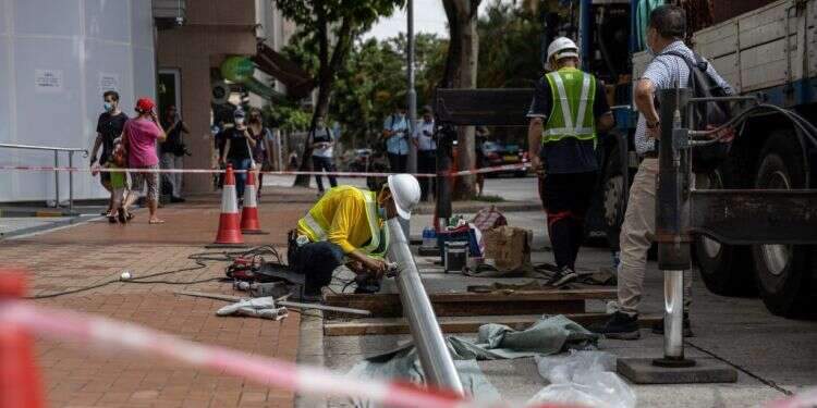 פועל מתקין מוט דגל מול המלון. צילום: EPA המשטרה החשאית של סין בהונג־קונג השתלטה על מלון מפואר מול מוקד ההפגנות