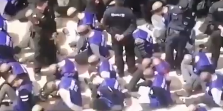 אויגורים כפותים בתחנת רכבת בסין. צילום מסך מטוויטר לפני שתזמינו מסין גאדג'ט מגניב או שמלה הורסת, חשבו על האויגורים