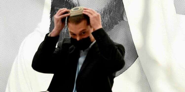 חבר במשלחת היי-טק ישראלית מסדר את הכיפה ליד פוסטר של מושל דובאי השייח מוחמד בין-ראשיד אל-מקטום. צילום: AFP ראשי