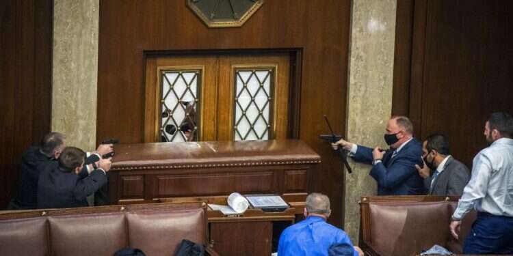 מאבטחים באקדחים שלופים מול דלתות בית הנבחרים החסומות. צילום: ביל אולירי, הוושינגטון פוסט ההתפרעות בקפיטול: זעם, ניפוץ חלונות, ביזה ואלימות