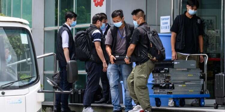 הרשויות מוציאות ציוד ומחשבים מבניין מערכת העיתון. צילום: AFP "סכנה לביטחון הלאומי": המשטרה פשטה על העיתון בהונג-קונג