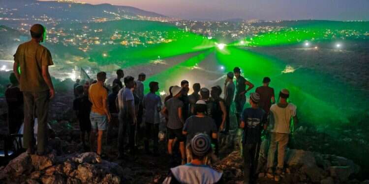 תושבי אביתר מביטים במפגינים פלסטינים, שמכוונים לעברם קרני לייזר. צילום: AFP זעם בשמאל על ההסכם עם אביתר: "דורשים התערבות מיידית"