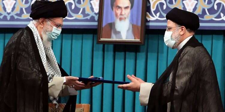 ראיסי (מימיו) מקבל את כתב המינוי מחמינאי. צילום: AFP