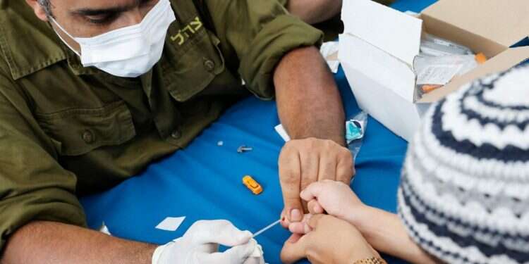 חייל מילואים מבצע בדיקה סרולוגית לילד בנתניה לקראת פתיחת שנת הלימודים. צילום: AFP 11 בספטמבר של מערכת החינוך