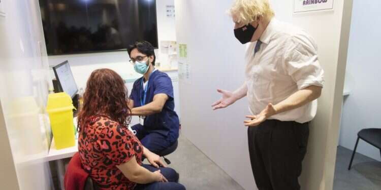 ראש ממשלת בריטניה בוריס ג'ונסון מעודד מתחסנת לקורונה. צילום: AP התפשטות האומיקרון: מערכת הבריאות בבריטניה מתכוננת לגל אשפוזים