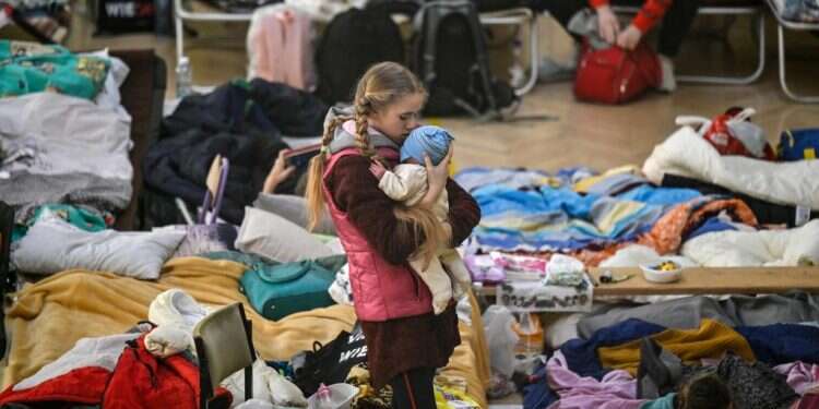 ילדה מחזיקה את אחיה הפעוט במחנה פליטים בגבול אוקראינה-פולין. צילום: AFP בזמן שההפצצות נמשכות: התקדמות במו"מ בין אוקראינה לרוסיה