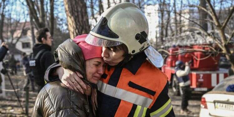 עובדת חירום מרגיעה אזרחית שפונתה מבניין בוער בקייב. צילום: AFP "פוטין פושע מלחמה": ארה"ב תספק ציוד צבאי נוסף לאוקראינה