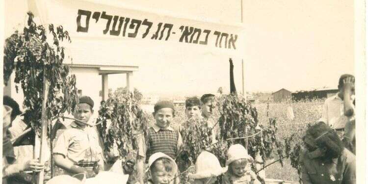 הילד נאלץ להתעטף באדום לכבוד חג הפועלים ואינו יכול לשאת זאת. חגיגת אחד במאי בגן ילדים בקריית־אתא, שנות הארבעים. צילום: בית פישר, קרית אתא