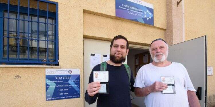 שמעון קפלן (מימין) ובנו שמחה אורי קפלן, פליטים יהודיים מאוקראינה בפתח לשכת האוכלוסין וההגירה בצפת, אוחזים בידיהם את תעודות הזהות החדשות, הבוקר. צילום: אייל מרגולין - ג׳יני