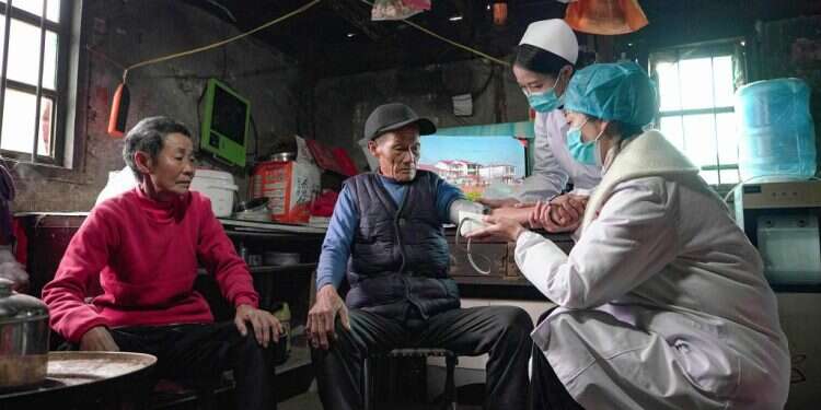 אחיות עורכות בדיקה רפואית בביתם של תושבים בדרום־מערב סין שאינם יכולים לצאת מביתם. צילום: איי.אף.פי מאפס הדבקה למאה: גם בישראל מביעים חשש מנחשול הקורונה בסין