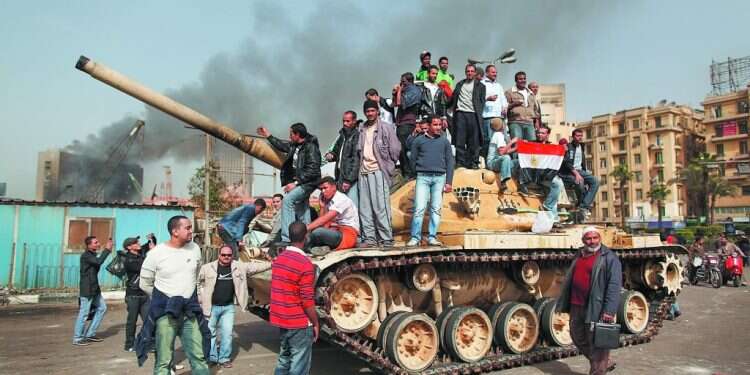 האלימות דוכאה באמצעות הטלת פחד. מפגינים על טנק בכיכר תחריר, אוגוסט 2011. צילום: גטי אימג'ס "המפגינים מקהיר החלו לעלות על הרכב שלנו, ומסביב יריות. אמרתי לעצמי – מפה כבר לא נצא"