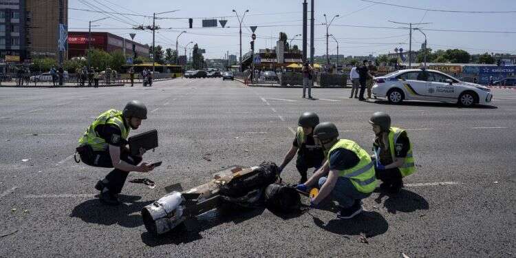 שוטרים אוקראינים ליד אחד הטילים שנורה על קייב, היום. צילום: Evgeniy Maloletka, AP טילים לאור יום: רוסיה במתקפה נדירה על קייב