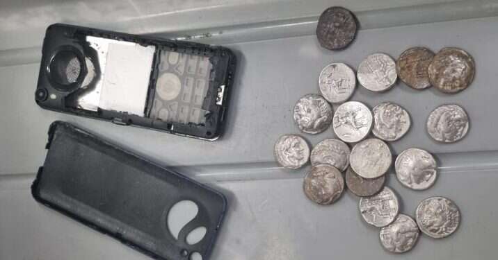 המטבעות העתיקים שנפתסו במכשיר הטלפון הנייד. צילום: דוברות מתפ״ש ניסה להבריח מטבעות עתיקים בתוך טלפון – ונתפס