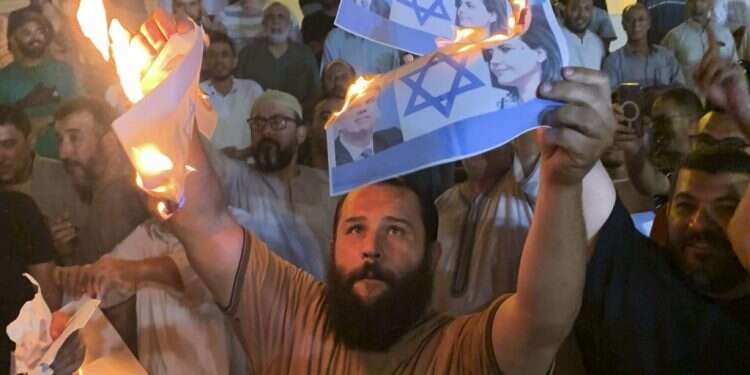 מפגינים בלוב מציתים דף עם דגל ישראל ותמונותיהם של שר החוץ הישראלי אלי כהן ושרת החוץ הלובית. צילום: Yousef Murad, AP הפגישה הסודית עם ממשלת לוב: במקום נורמליזציה קיבלנו פיאסקו