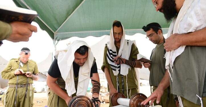 חיילים מתפללים בשטחי כינוס לפני מבצע צוק איתן. צילום: מנדי הכטמן, פלאש 90 הלכות מלחמה: מותר לחזור לבסיס בשבת מהתרעננות בבית