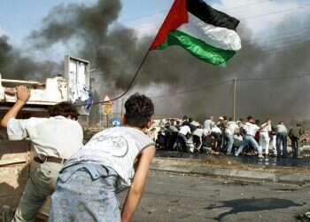 פלסטינים מניפים את דגל אש"ף במהלך עימותים בצפון רמאללה במהלך האינתיפאדה השנייה. צילום: יולה מונקוב - פלאש 90