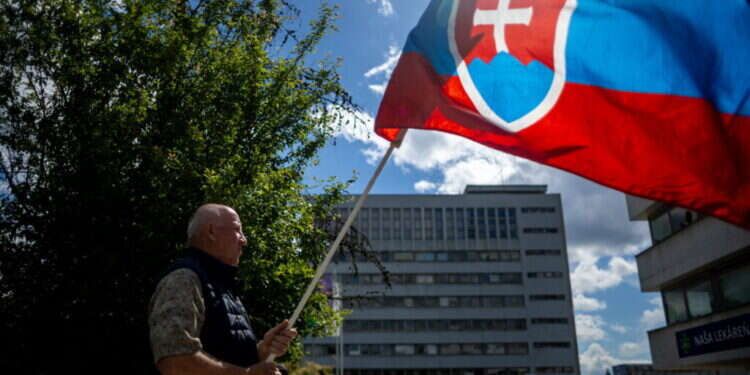 אדם מניף את דגל סלובקיה. צילום: EPA אדם מניף את דגל סלובקיה מחוץ לבית החולים שבו מאושפז ראש הממשלה רוברט פיצו