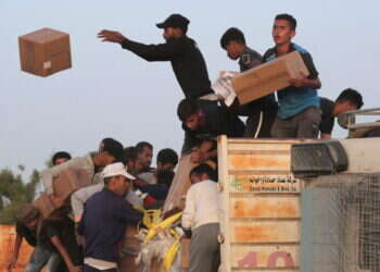 עזתיים מרוקנים ציוד ממשאיות הסיוע שנכנסו לרצועת עזה מהמזח האמריקני. צילום: AFP