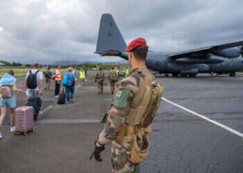 המרד בקלדוניה החדשה. חייל ניו־זילנדי מאבטח השבוע תיירים שנמלטים מהארכיפלג במטוס צבאי מיוחד. צילום: איי.אף.פי