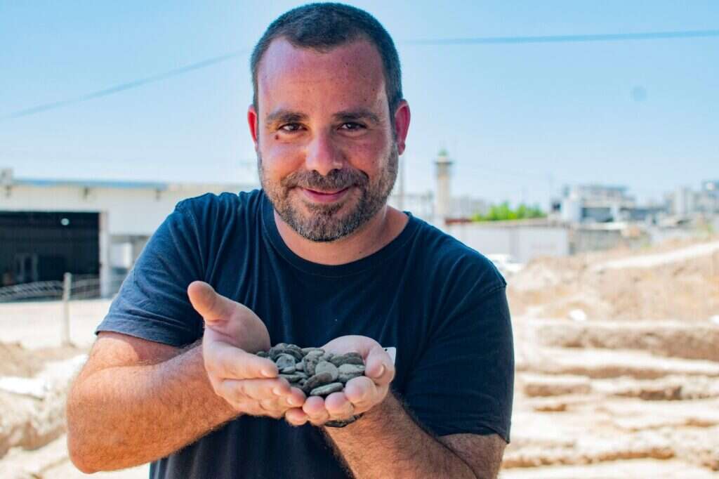 הארכיאולוג שחר קריספין מחזיק את מטמון המטבעות לאחר מציאתו. צילום יולי שוורץ