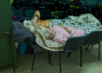 שתי אחיות )ניצולות שואה(, אחת מאשקלון ואחת מבאר שבע, ישנות על כיסאות במבנה ציבורי בזמן מבצע צוק איתן. רינה קסטלנובו, 2014