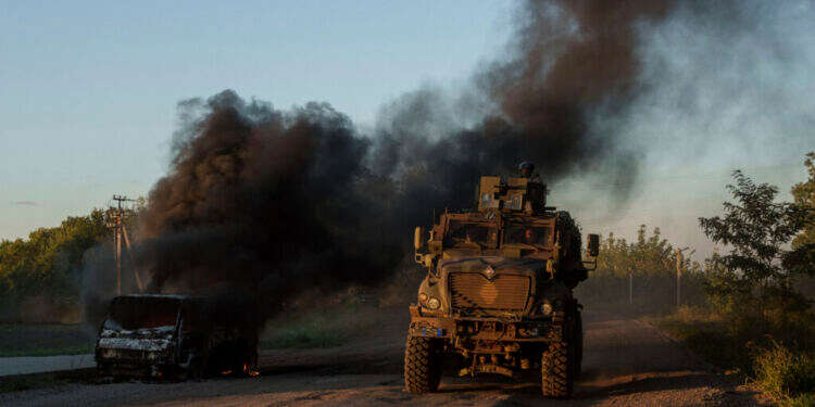 משוריין של צבא אוקראינה חולף ליד מכונית בוערת סמוך לגבול, שבוע שעבר. צילום: איי.פי הפלישה האוקראינית הנועזת לרוסיה משנה את נרטיב המערכה