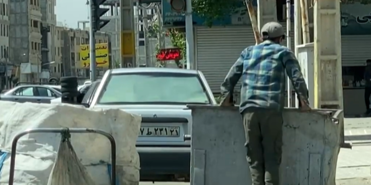 צעיר קופץ לפח כדי לחפש אוכל בטהראן. צילום מסך מיוטיוב צעיר קופץ לפח כדי לחפש אוכל בטהראן. צילום מיוטיוב