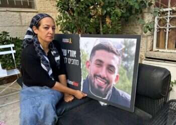 עינב דנינו עם תמונה של בנה אורי ז"ל בחצר ביתה שבשכונת רמות. צילום: עמיאל ירחי