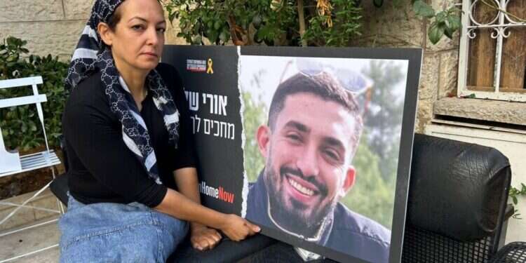 עינב דנינו עם תמונה של בנה אורי ז"ל בחצר ביתה שבשכונת רמות. צילום: עמיאל ירחי