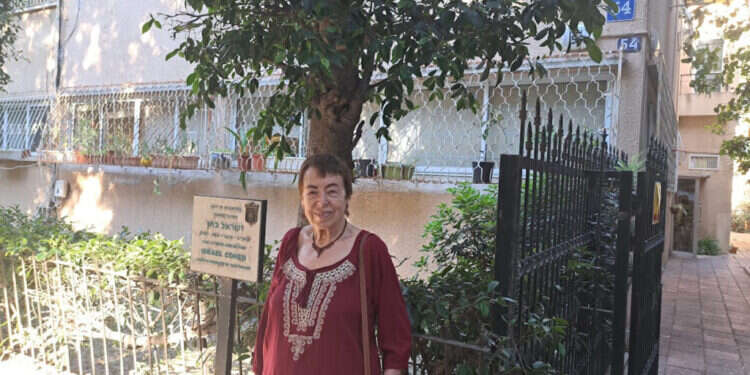 מאביה למדה על חשיבותם של ספרים. פרופ' גוברין ליד בית ילדותה. בשלט מוזכר אביה, הסופר והעורך ישראל כהן. צילום: יאיר בן־חיים