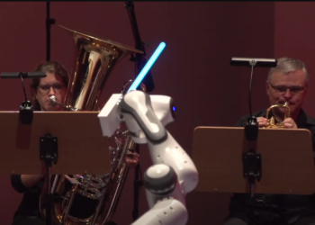 רובוט בעל שלוש זרועות מנצח על תזמורת באמצעות חרבות אור