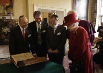 הרב זקס והמלכה אליזבת מתבוננים בכתב היד העתיק ביותר של התנ"ך ששרד באנגליה, הידוע כקודקס ולמדונה I. לונדון, 2012. צילום: אי. אף. פי