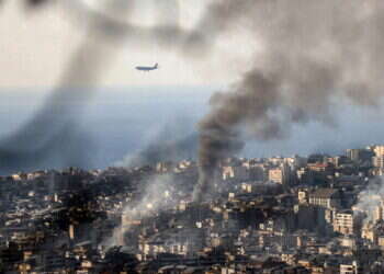 מטוס נוחת בשדה התעופה בביירות על רקע העשן מתקיפות חיל האוויר הישראלי. צילום: AFP