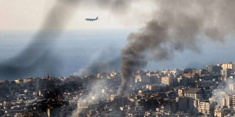 מטוס נוחת בשדה התעופה בביירות על רקע העשן מתקיפות חיל האוויר הישראלי. צילום: AFP
