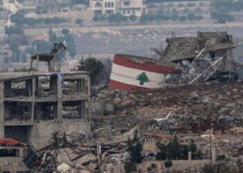 דגל לבנון על רקע ההריסות בכפר בדרום המדינה. צילום: EPA