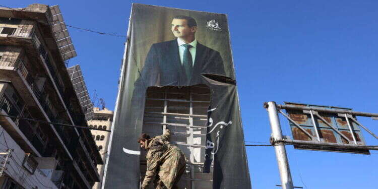 מורד סורי קורע כרזה של נשיא סוריה, בשאר אל-אסד. צילום: EPA המהפכה הושלמה: דמשק נכבשה, אסד ברח למקום לא ידוע