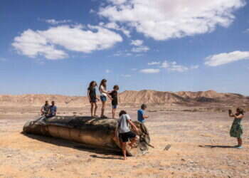 מטיילים על שרידי טיל איראני בים המלח. צילום: מנחם כהנא - AFP