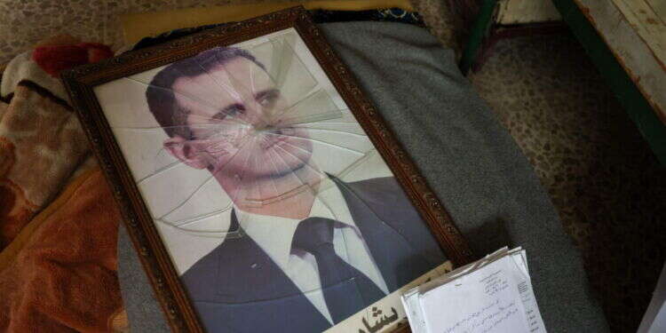 דיוקנו של נשיא סוריה בשאר אל-אסד מצולם כשמסגרתו שבורה, במתקן של זרוע הביטחון המדיני של המשטר הסורי בפאתי העיר המרכזית חמה, לאחר כיבוש האזור על ידי כוחות אנטי-ממשלתיים. צילום: AFP מדמשק עד טהרן: למה המרד בסוריה הצליח ובאיראן לא?