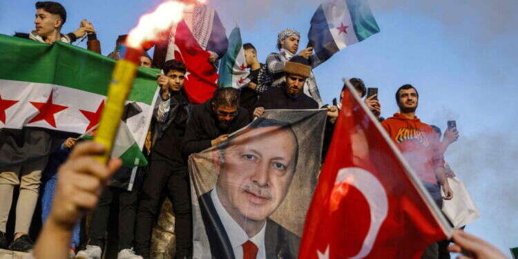 דגלי טורקיה וסוריה לצד תמונה של נשיא טורקיה רג'פ טאיפ ארדואן, לאחר נפילת שלטון אסד בסוריה. צילום: AFP חוסר עקביות: האם סוריה תהפוך לשדה קרב בין טורקיה לישראל?