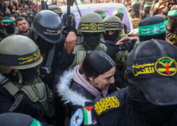 ארבל יהוד מובלת על ידי המחבלים בעת שחרורה מהשבי, לפני עלייתה לרכב הצלב האדום. צילום: AFP אגם ברגר, ארבל יהוד וגדי מוזס שוחררו משבי חמאס