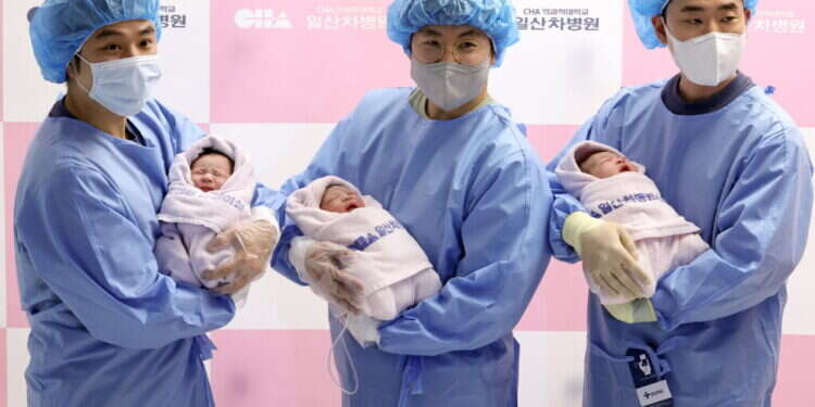 אבות טריים בקוריאה הדרומית מחזיקים את ילדיהם שנולדו בינואר האחרון. צילום: EPA